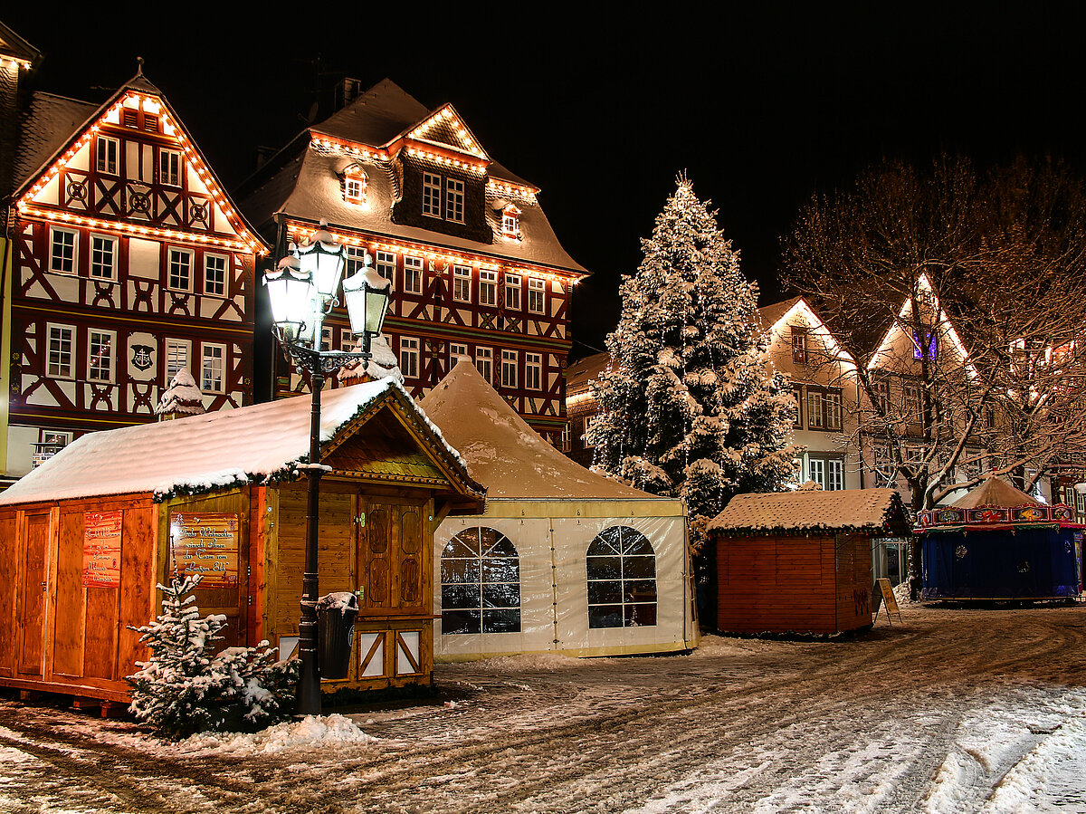 [Translate to Französisch:] Weihnachtsmarkt vor beleuchteten Fachwerkhäuser im Schnee