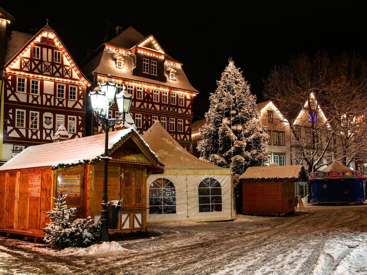 [Translate to Französisch:] Weihnachtsmarkt vor beleuchteten Fachwerkhäuser im Schnee
